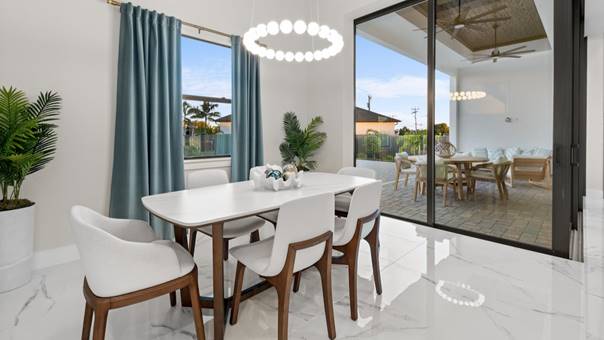 Eetkamer met rustige inrichting, glazen schuifpui, zachte kleuren en natuurlijk daglicht voor een serene sfeer