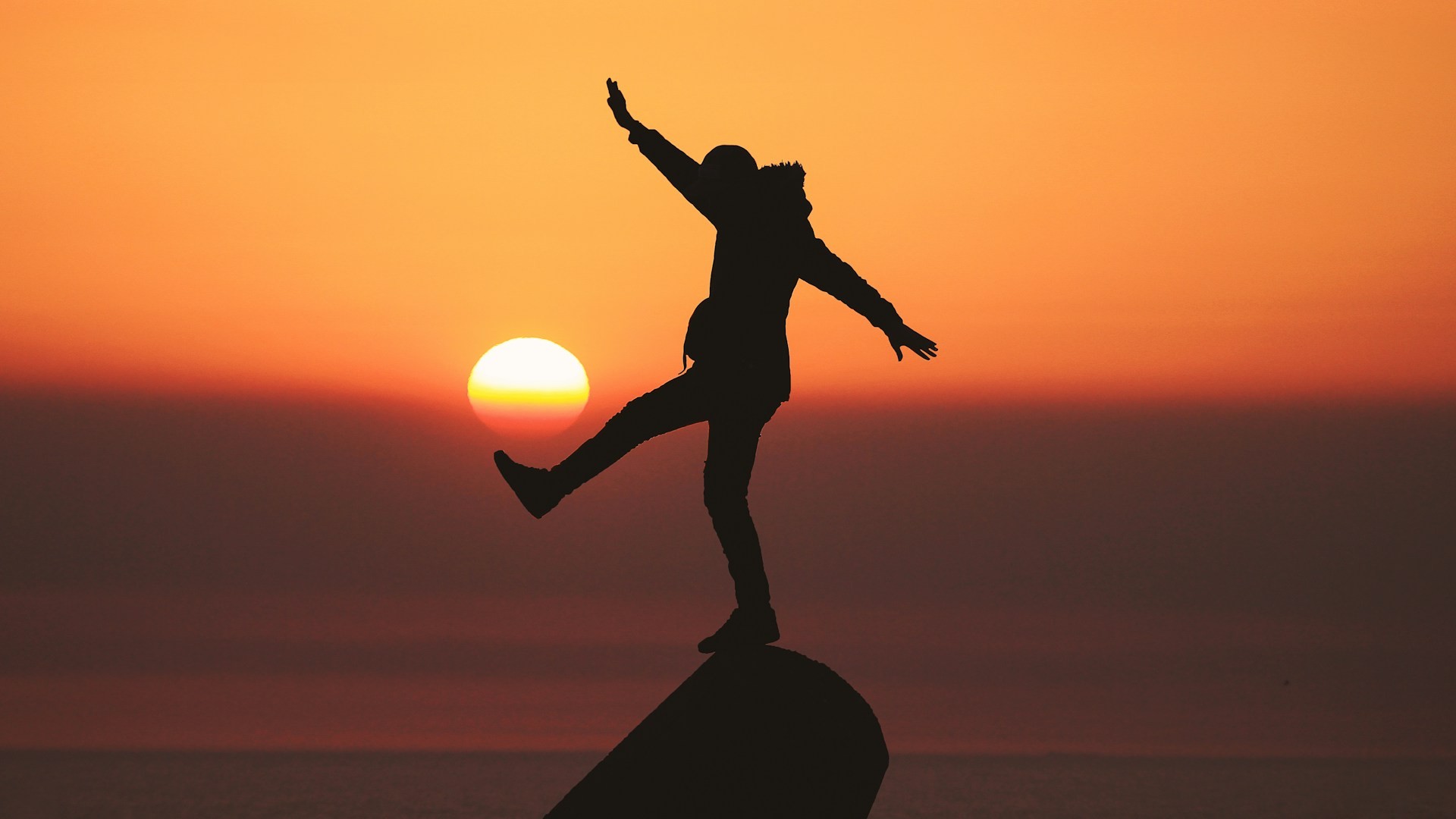 Silhouet van persoon die balanceert op rots bij zonsondergang als symbool voor balans verbeteren