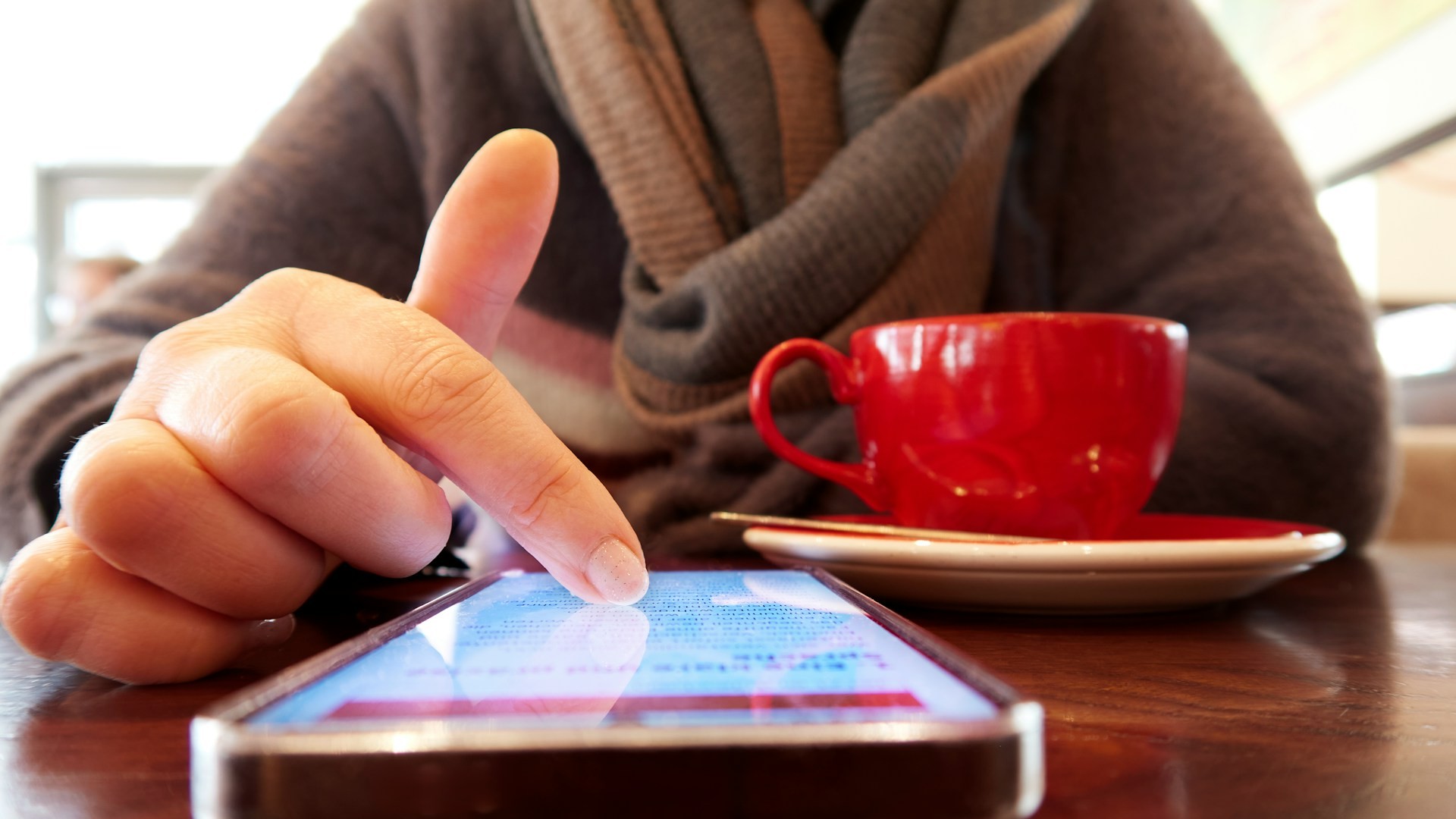 Telefoonroutine tijdens koffiemoment waarbij iemand bewust op smartphone kijkt aan tafel