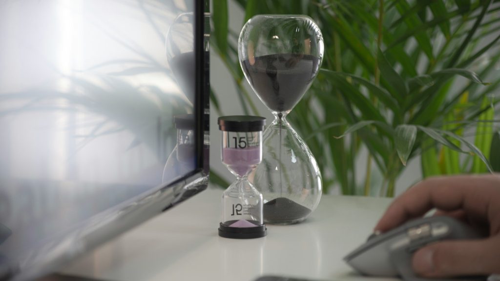 Telefoonroutine en focus met zandloper naast scherm tijdens werkmoment zonder afleiding