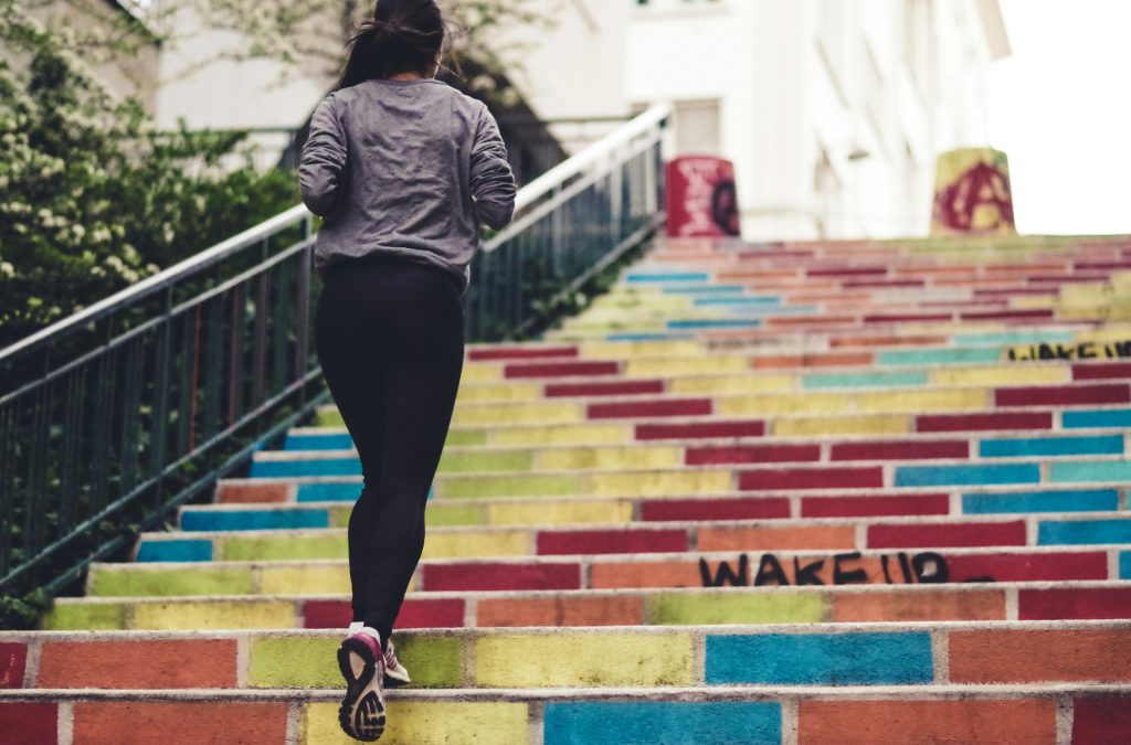 Vrouw rent trap op in de buitenlucht als voorbeeld van een actieve leefstijl en dagelijkse beweging