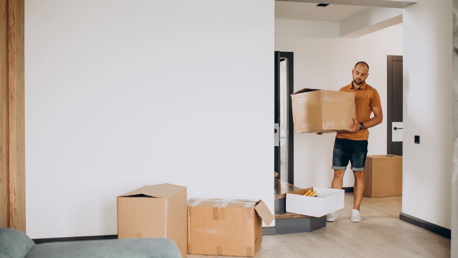 Man tilt verhuisdoos in lege woning tijdens verhuizing naar nieuw huis